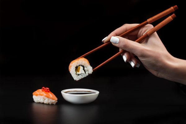 hand-holds-sushi-bowl-with-soy-sauce-black-table (1)